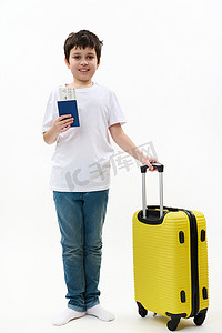 全尺寸旅行者男孩，穿着休闲服，拿着手提箱和登机牌，在白色背景中孤立地行走。