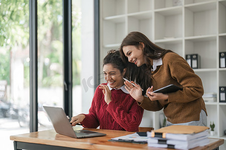 不同职业的女性摄影照片_在现代办公室开会时，两位不同的女性在会议室的桌子上一起工作时微笑