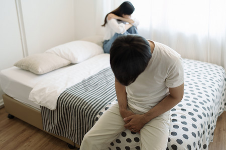年轻夫妇躺在家里卧室的床上，女人穿着内衣睡觉，悲伤、沮丧的男人思考人际关系，家庭有性问题，勃起功能障碍概念。