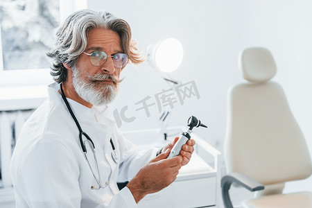 耳鼻喉科诊所室内，头发灰白、胡须白大衣的高级男医生画像