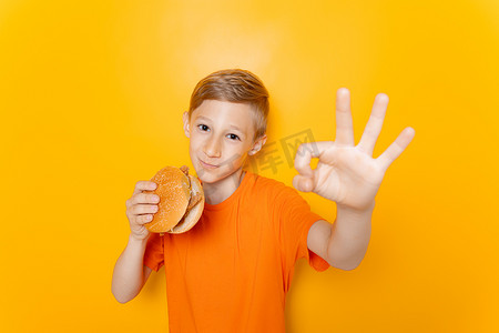 一个男孩吃汉堡包，在黄色背景下表现得很好