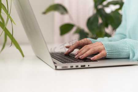 办公室的电脑摄影照片_特写女商人手打字和使用笔记本电脑键盘搜索技术网络在工作场所或在家工作的办公桌上工作和工作。