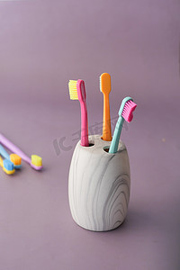 紫色背景中白色杯子中的彩色牙刷
