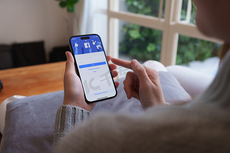 泰国清迈 - 2023 年 4 月 21 日：女性手使用 iPhone 14 和 Metaverse 的 facebook 应用程序。