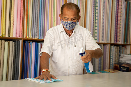 使用消毒剂在医用面罩消毒台上的店主 — 用布或消毒剂喷雾清洁台面上的灰尘，以防止冠状病毒或 covid-19 感染。