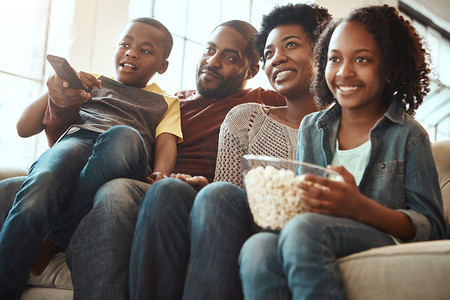 黑人家庭一起在沙发上看电视看电影、电影和卡通片，在客厅里度过美好的时光。