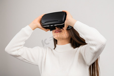 vr虚拟现实摄影照片_惊讶的年轻女孩在虚拟现实中使用 vr 眼镜耳机探索 metaverse。