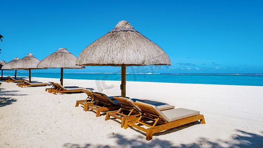 毛里求斯带棕榈树和白沙蓝海的热带海滩以及带伞的沙滩床