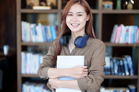 一张笑脸在图书馆找课本的亚洲年轻女性的画像