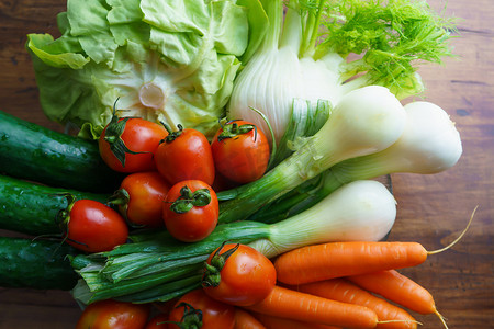 新鲜生蔬菜的健康营养：木桌复制空间上的一组沙拉配料、生菜、西红柿、黄瓜、茴香、葱和胡萝卜的平躺顶视图