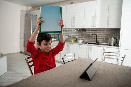 白种人聪明的十几岁男孩，小学生使用数字平板电脑在家里愉快地上在线语言课