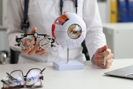 眼科诊断摄影照片_眼科医生拿着眼镜选择镜片和人眼的解剖学