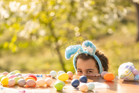 快乐的少女在花园里戴着带复活节彩蛋的兔耳