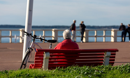 坐在长凳上的资深骑自行车者看海