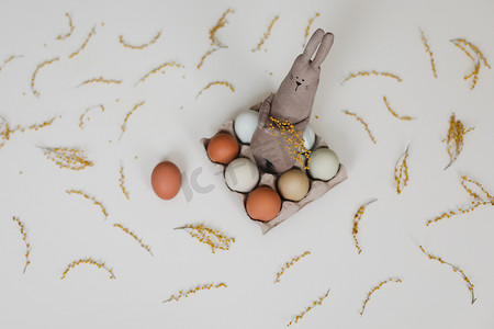 有趣的手工兔子玩具，配有彩色鸡蛋和黄色含羞草花。