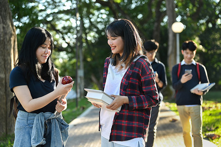 快乐的大学生去上大学课，在大学校园里边走边聊天。