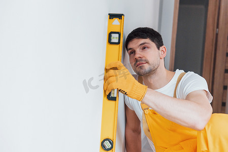 黄色制服的杂工检查墙的水平。