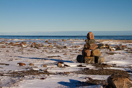 北极景观 — 在阳光明媚的日子里，努纳武特积雪覆盖的北极苔原上的 Inuksuk 或 Inukshuk 地标