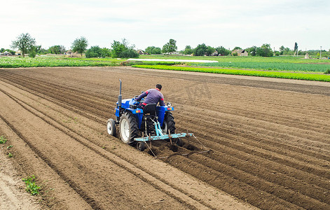 一位农民在拖拉机上耕地以进一步播种作物。