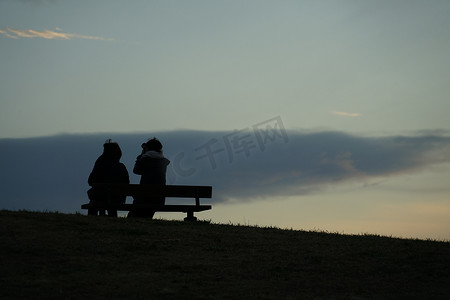 父母和孩子坐在有日落山的长凳上