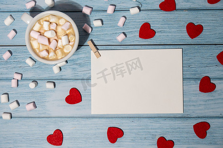 木制背景上用红心、白杯咖啡和棉花糖模拟的贺卡或邀请卡。