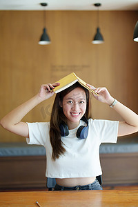 一位戴着耳机、头上拿着笔记本的亚洲少女画像，脸上露出快乐的表情