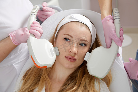 几位医生的手拿着激光设备在女性脸上的概念美容和美容图像。