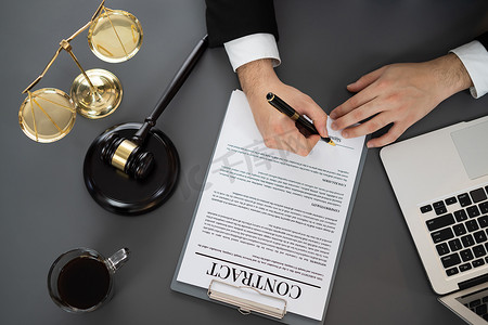 顶视图律师在律师事务所办公室概念中签订合同。