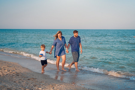 孩子爸爸妈妈摄影照片_爸爸妈妈和孩子一起度过家庭假期父母爸爸妈妈和儿子一起散步享受海滩
