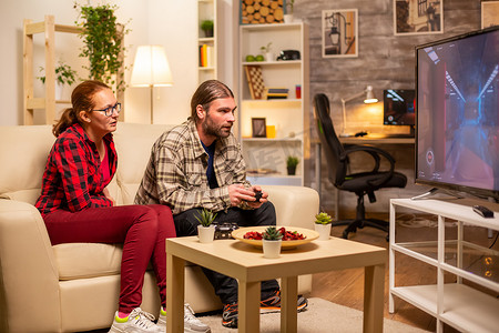 情侣深夜在客厅的大屏幕电视上玩电子游戏