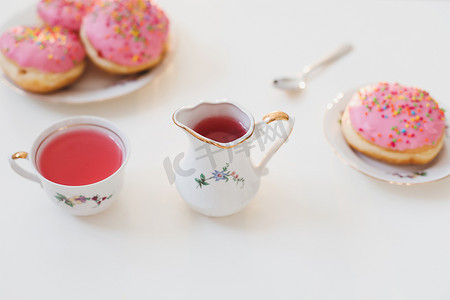 早餐，五颜六色的粉红色饮料和白桌上的甜甜圈。