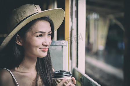 兰芳园丝袜奶茶摄影照片_亚洲女旅客在火车上喝咖啡，开心