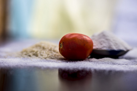 木表面玻璃碗中的米粉和西红柿面膜，以及生米、西红柿和米粉。用于治疗油性皮肤。