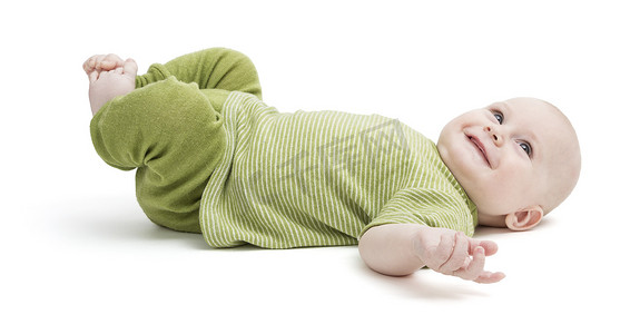 孩子衣服摄影照片_穿着绿色衣服仰面躺着的快乐蹒跚学步的孩子