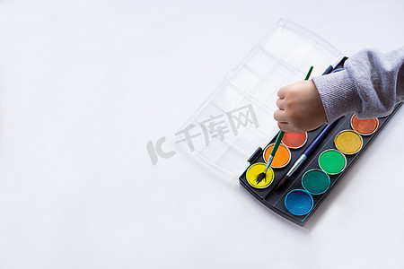 儿童手拿着画笔的特写，会用颜色画画。