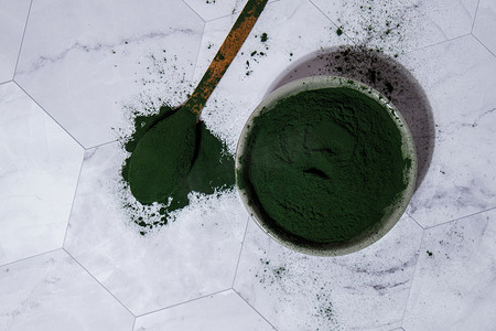 蓝绿藻小球藻和螺旋藻粉用木勺放在碗里。