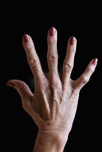 妇女节背景红色摄影照片_黑色背景下涂着红色指甲油的高级女性手
