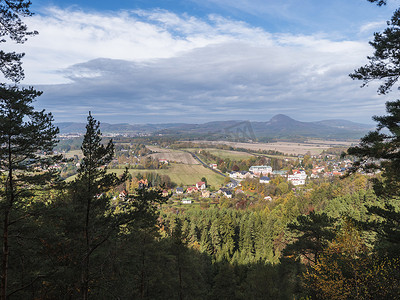 从 Hrabencina vyhlidka 瞭望台看 Luzicke hory 的 Sloup v cechach 村，Lusatian 山脉有秋天的落叶和针叶林和青山、蓝天、白云