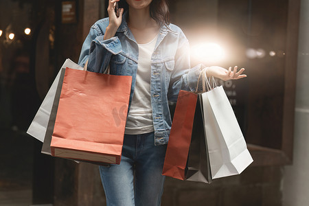 亚洲时尚女性提着购物袋在购物中心散步，同时进行限时促销