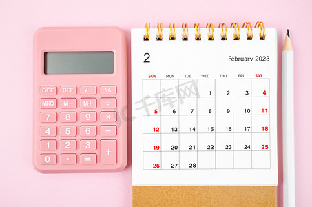 英语活动背景摄影照片_2023 年 2 月的 2023 年台历，带有粉红色背景的计算器。