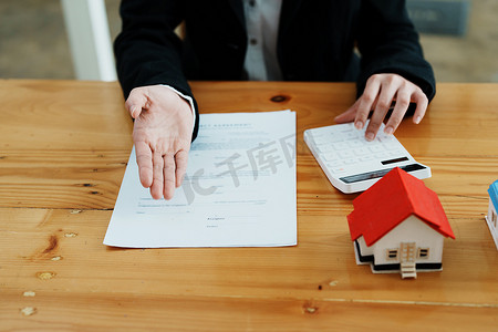 担保、抵押、合同、合同、签署、房地产经纪人或银行职员拿着计算器，在签署交易前向客户提交购买房屋的出价