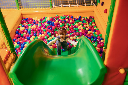 穿着休闲服的快乐小女孩在儿童游戏中心玩得开心