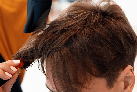 特写合格的亚洲女性理发师为男性顾客理发。