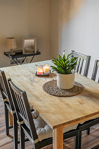 浅色装饰元素摄影照片_木制餐桌的顶部视图，椅子和装饰元素植物、蜡烛、枕头在浅色墙壁背景上。
