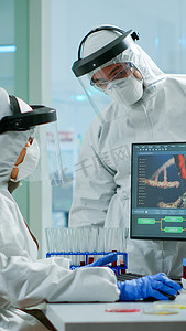 身穿防护服的科学家团队在电脑前争论病毒的发展