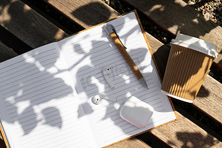 用带无线耳机的纸质笔记本带走工艺回收纸杯中的咖啡。