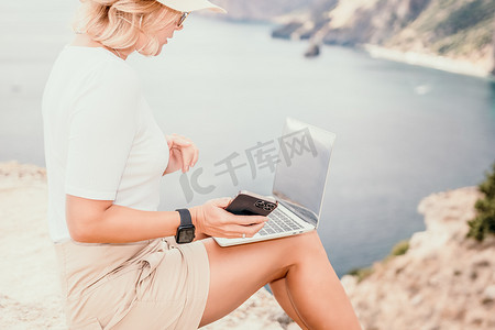 数字游牧民族，在海边使用笔记本电脑工作的女商人。
