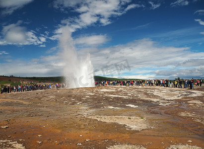 冰岛，STROKKUR，2016 年 7 月 26 日：Strokkur 间歇泉喷发黄金圈，一大群穿着五颜六色的游客拍照等待间歇泉喷发。 