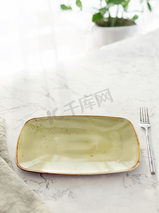 白色大理石桌上带叉子的空绿色矩形板