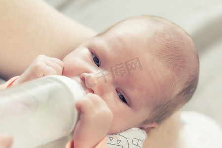 可爱的新生儿正在喝奶瓶里的牛奶